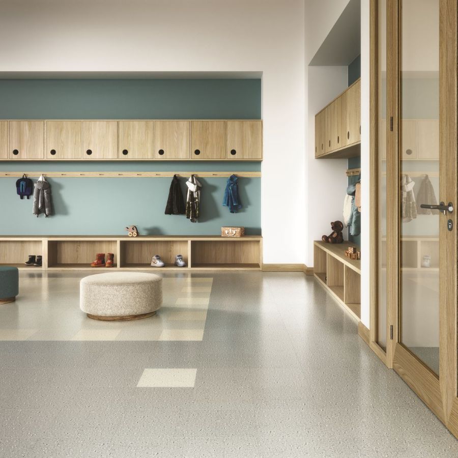 Common area with benches, wall cabinets, and hanging coats. Iliad glue-down VCT flooring